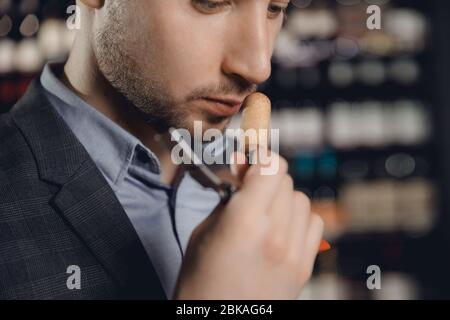 Sommelier sniffs smell of cork from bottle of red wine, tests drink Stock Photo