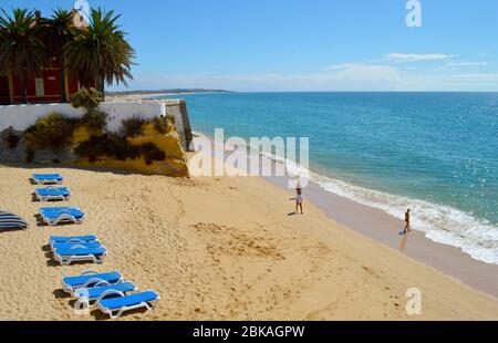 Tourists Enjoying Sunny Weather On Armacao De Pera Beach On The Algarve 