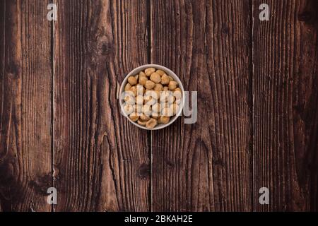 Raw hazelnut on old wooden table. Unroasted hazelnuts in white bowl and scattered hazelnuts around. Stock Photo