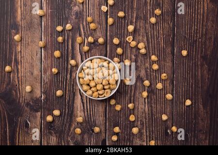 Raw hazelnut on old wooden table. Unroasted hazelnuts in white bowl and scattered hazelnuts around. Stock Photo