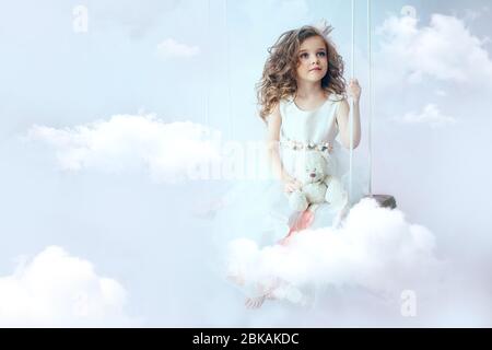 little girl is sitting on the cloud Stock Photo