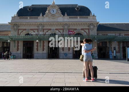 Couple hugging as man looks at his phone Stock Photo