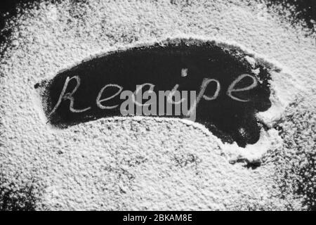 Headline recipe sprinkle flour on a black table. Banner recipe handwritten word. Stock Photo