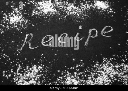 Headline recipe sprinkle flour on a black table. Banner recipe handwritten word. Stock Photo