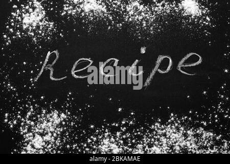 Headline recipe sprinkle flour on a black table. Banner recipe handwritten word. Stock Photo