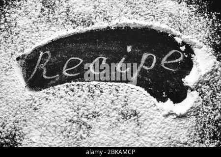 Headline recipe sprinkle flour on a black table. Banner recipe handwritten word. Stock Photo