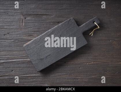 black empty wood cutting board on dark kitchen table, top view Stock Photo