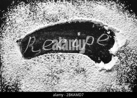 Headline recipe sprinkle flour on a black table. Banner recipe handwritten word. Stock Photo