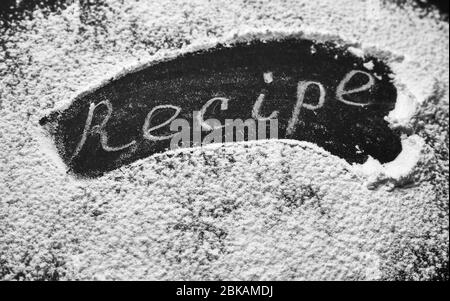 Headline recipe sprinkle flour on a black table. Banner recipe handwritten word. Stock Photo