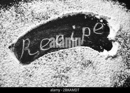 Headline recipe sprinkle flour on a black table. Banner recipe handwritten word. Stock Photo