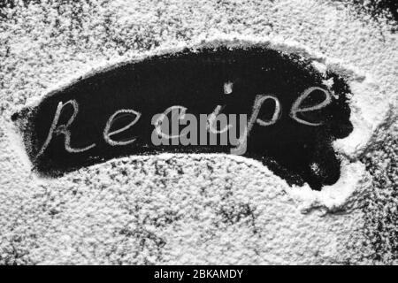 Headline recipe sprinkle flour on a black table. Banner recipe handwritten word. Stock Photo