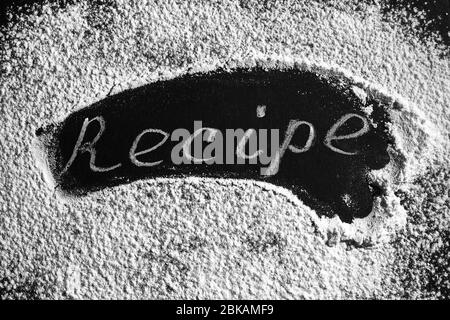 Headline recipe sprinkle flour on a black table. Banner recipe handwritten word. Stock Photo