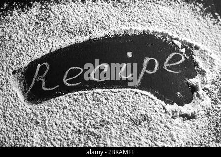 Headline recipe sprinkle flour on a black table. Banner recipe handwritten word. Stock Photo