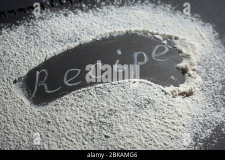 Headline recipe sprinkle flour on a black table. Banner recipe handwritten word. Stock Photo