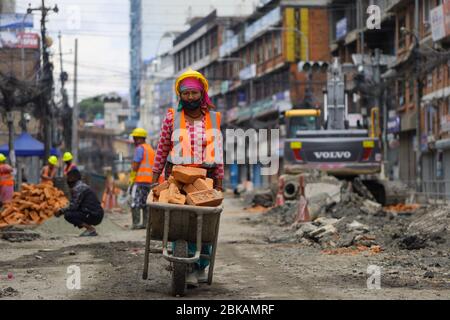 Kathmandu, Nepal. 03rd May, 2020. A Nepalese woman worker pushing a wheelbarrow full with bricks at drainage construction site during the nationwide lockdown imposed to combat the spread the novel coronavirus (COVID-19). in Kathmandu, Nepal on May 03, 2020. (Photo by Subash Shrestha/Pacific Press) Credit: Pacific Press Agency/Ģ����ý Live News Stock Photo