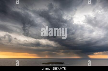 Stormy sky and rainclouds over a small island (Illa de Sanitja O dels Porros) off Cap de Cavalleria in the north of Menorca, Spain Stock Photo