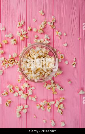 Flat lay popcorn in a glass bowl and sprinkled popcorn around it.