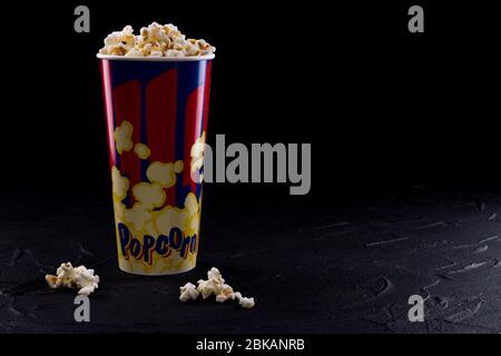 Full popcorn in classic popcorn box on very dark background. Stock Photo
