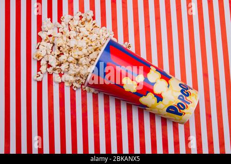 Close up popcorn was scattered from box on striped background. Stock Photo