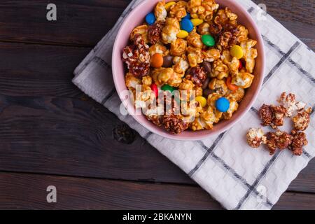 Salted dark chocolate popcorn with colorful chocolate buttons in bowl on napkin. Stock Photo