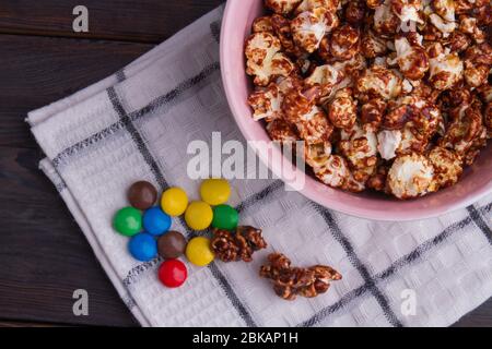 Homemade delicious caramel popcorn with colorful buttons on white napkin. Stock Photo