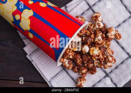 Close up chocolate popcorn scattered from bucket on a towel. Stock Photo