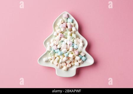 mini marshmallows on fir shape plate, christmas snack on pink background, top view Stock Photo