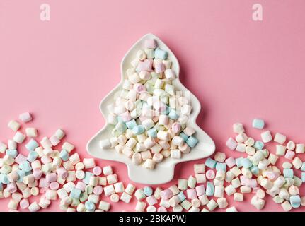mini marshmallows on fir shape plate, christmas snack on pink background, top view Stock Photo