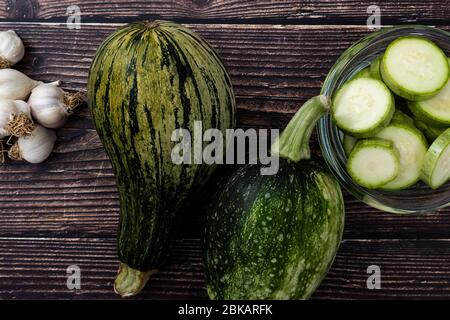 Top view of zucchinis and sliced zucchini on wood background. Fresh and organic vegetables from garden. Stock Photo