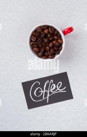 Coffee cup with red handle filled with roasted beans. Stock Photo