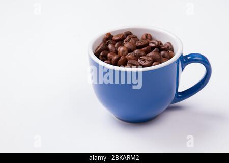 Blue cup full of coffee beans isolated on white. Stock Photo