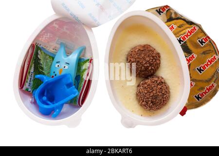 Kinder Joy egg with surprise showing both halves opened with one showing contents and the other the toy inside set on white background Stock Photo