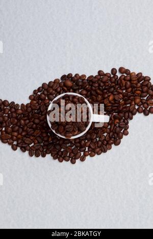 Cup full of coffee beans standing on a pile of coffee. Stock Photo