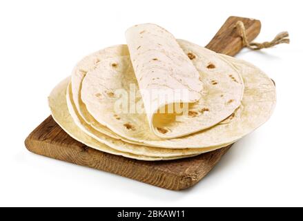 Stack of homemade wheat flour tortilla on wooden cutting board isolated on white background Stock Photo