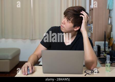 Asian officer man work from home. Man work in action at home. Man with laptop working remotely via high speed internet connection. Communication techn Stock Photo