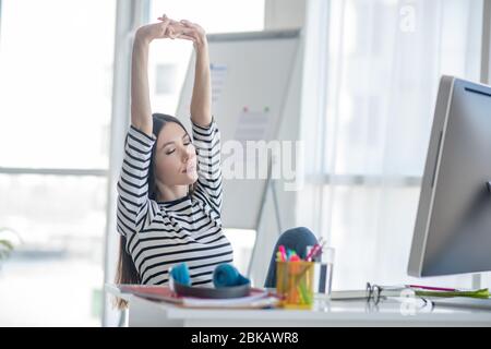 Pretty brunette woman stretching after a working day Stock Photo