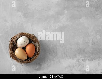 colorful easter eggs in wooden nest on grey background Stock Photo