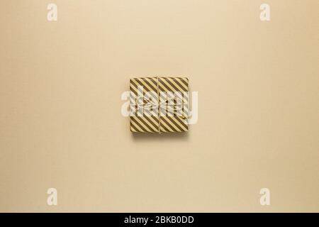 Gift box wrapped in striped kraft paper on brown background Stock Photo