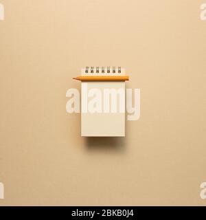 Empty kraft notepad with colored pencil on beige background. top view, copy space Stock Photo