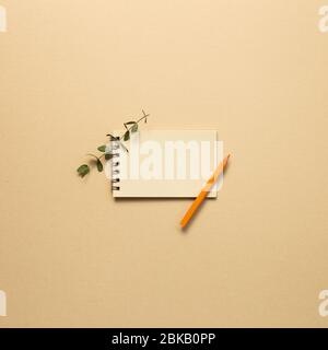 Empty kraft notepad with colored pencil on beige background. top view, copy space Stock Photo