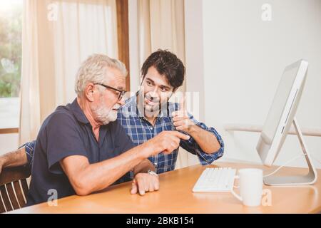 young man or son teaching his grandfather elderly dad learning to using computer at home. Stock Photo