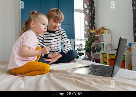 Children boy and girl doing homework using laptop at home Stock Photo