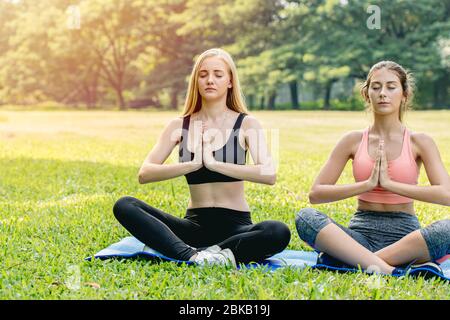 Beautiful girls teen friend do yoga for healthy in green park holiday sitting hand lotus eyes closed concentration posture. Stock Photo