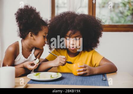 Little cute younger sister looking interesting her older sister try to learning eating vegetable. Stock Photo