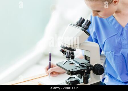 Young teen doctoral student in Medical university working study virus vaccine in school lab with microscope. Stock Photo