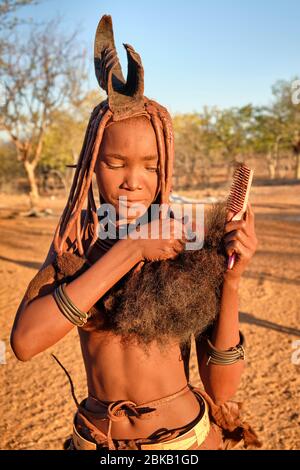 Batwa girl in traditional dress combing her hair at sunset. Stock Photo
