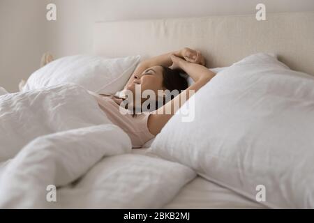Happy young woman stretch waking up in comfortable bed Stock Photo