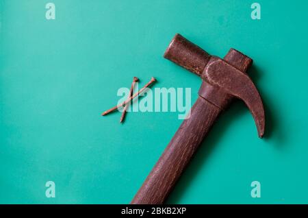 Vintage hammer and two rusty nails on a turquoise background. Old hammer with a pair of nails. Place for text. Flat lay. Stock Photo