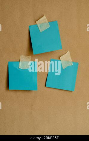 Colored paper for notes attached to the wall. Turquoise blank forms with adhesive tape on a plain wall. Front view. Training, business, media.. Stock Photo