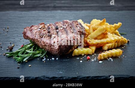 grilled beef fillet steak and fried potatoes on black slate background Stock Photo